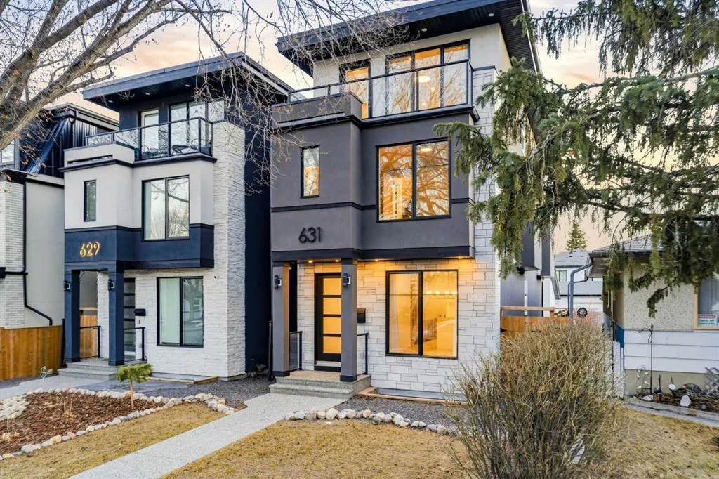 A pair of new inner-city Calgary homes at dusk, lights on
